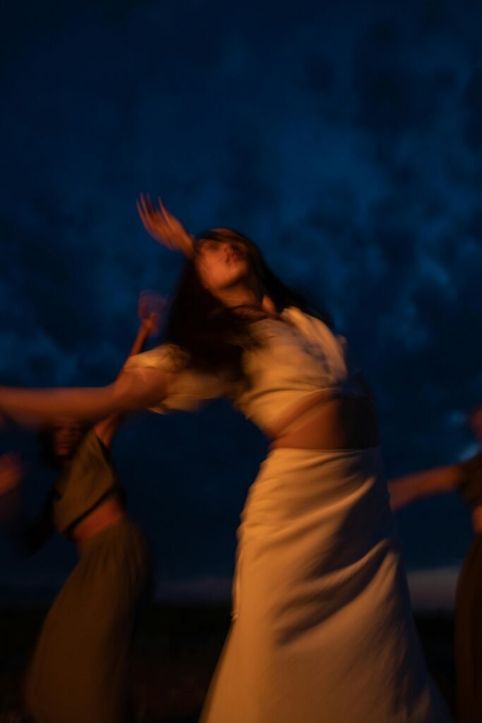 Blurred movement of women dancing joyfully during nighttime, creating an ecstatic and dreamy atmosphere.